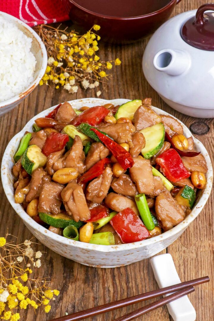 Kung Pao Chicken in a serving bowl with steamed rice on the side,