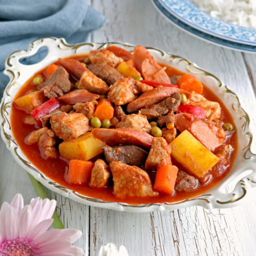 A tomato based pork stew with pork meat, liver, carrots, potatoes and green peas.