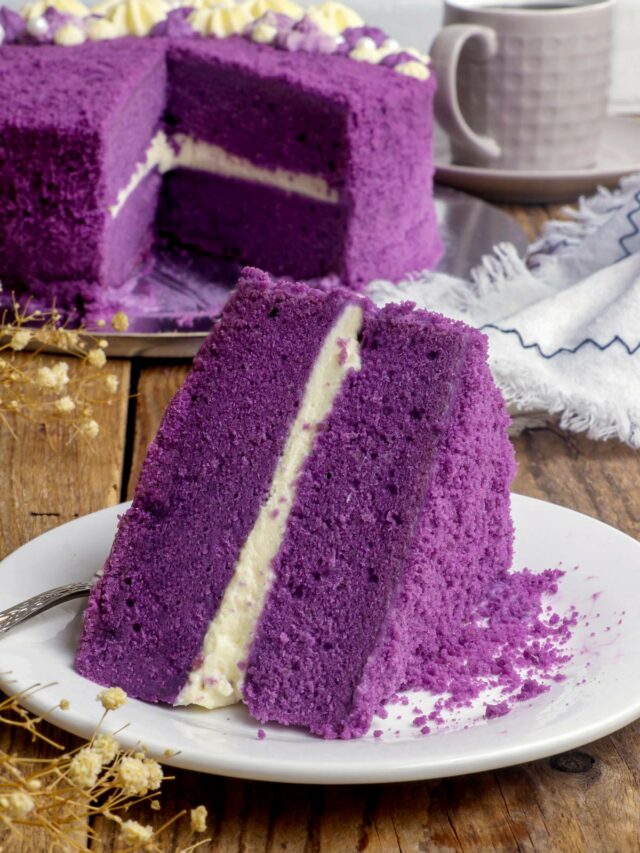 An ube cake slice on a serving plate layered with cream cheese frosting.